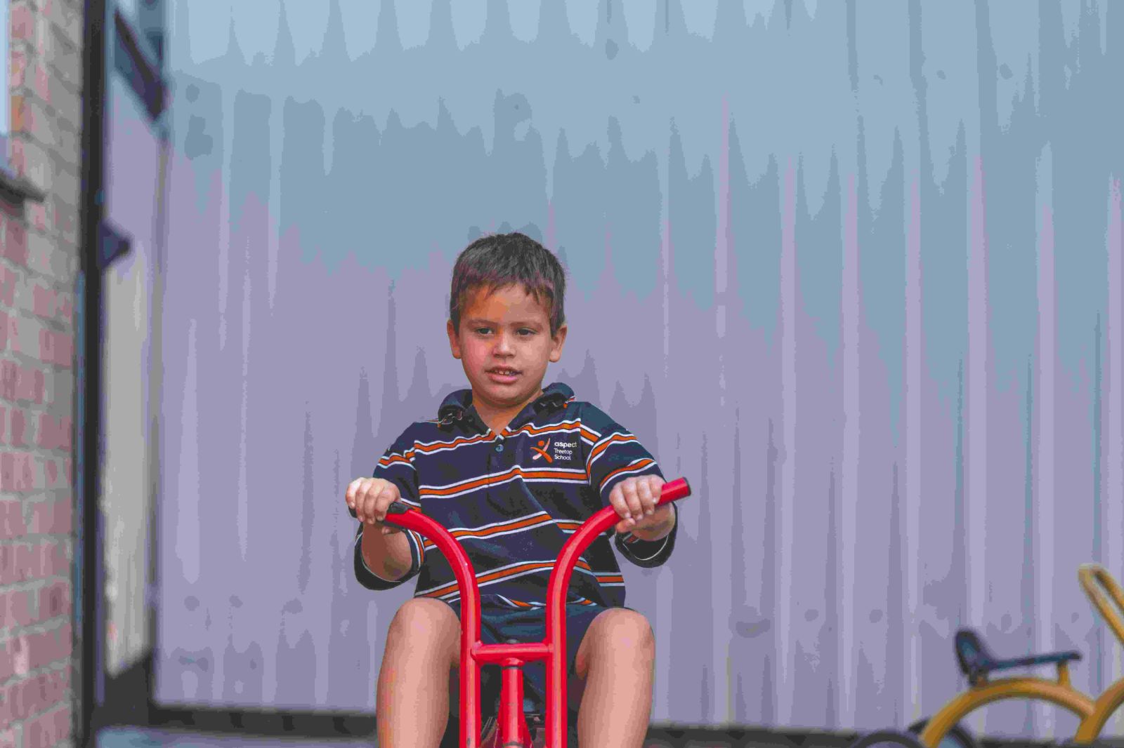 Student smiling and ridding a tricycle